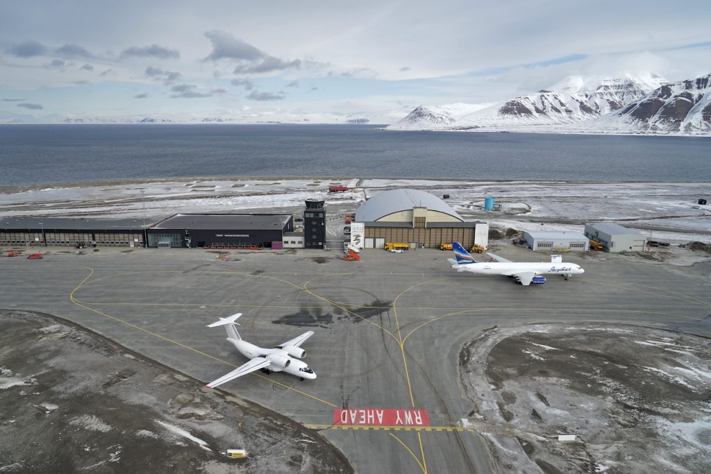 Photo réelle de l'aire de trafic de l'aéroport de Svalbard avec un Boeing 757 stationné et un avion Antonov AN 72 en circulation. 