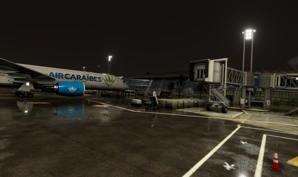 Vue nocturne d'un jet d'Air Caraïbes à l'aéroport international Martinique Aimé Césaire, avec aire de trafic mouillée et feux d'aérogare